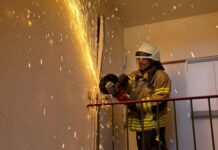 Die Ortsfeuerwehr öffnet Tür für hilflose Person mit Trennschleifer. Der Rettungsdienst musste schnell handeln
