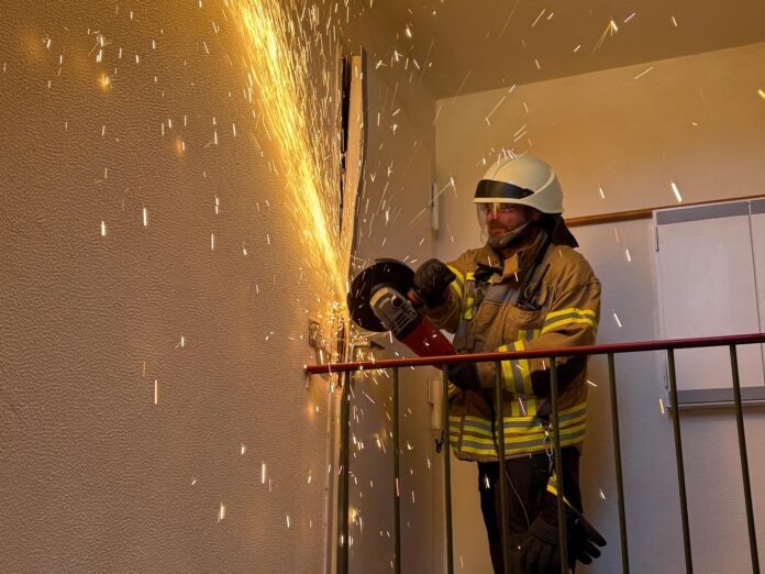 Die Ortsfeuerwehr öffnet Tür für hilflose Person mit Trennschleifer. Der Rettungsdienst musste schnell handeln