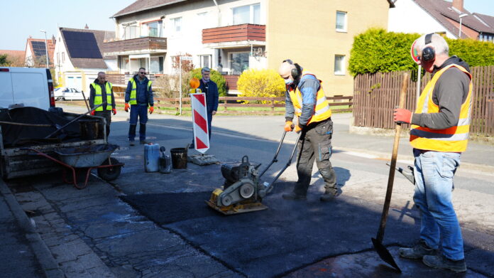 Fachgerechte Reparaturen am Westerwinkel: Beschäftigte der Straßenbaufirma glätten den heißen Asphalt und rütteln ihn ab. Bürgermeister Alexander Masthoff (Mitte) schaut mit prüfendem Blick :-) Frostschäden werden ausgebessert: Lange Frost, viele Reparaturen: Seelze stopft jetzt Schlaglöcher in 50 Straßen – mit Plan und Prioritätenliste und Blick