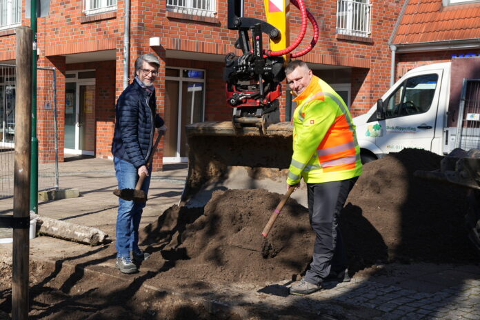 in neuer Baum für den Alten Krug: Bürgermeister Alexander Masthoff (links) und Richard Preece von der städtischen Abteilung Mobilität & Entwässerung versorgen die frisch eingesetzte junge Eiche mit sogenanntem Baumsubstrat. Neue Eiche bringt Herz zurück: Am Alten Krug ersetzt ein junger Baum die abgestorbene und Anfang März gefällte alte Eiche