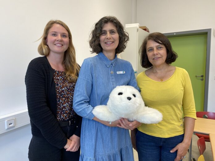 Schulsozialarbeiterin Surena Schröter, Sabine Langbehn, Leiterin der Stadtbibliothek Seelze, und Schulleiterin Gerda Schlinke von der Regenbogenschule Seelze mit der Therapierobbe „Paro“ Lesefreude mit Robbe in Seelze: Die Stadtbibliothek fördert mit Therapierobbe „Paro“ gezielt Kinder aus vier Schulen