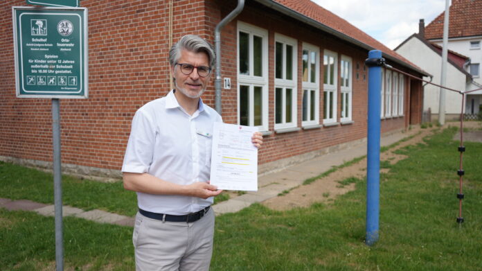 Bürgermeister Alexander Masthoff zeigt den Bewilligungsbescheid des Landes Niedersachsen für den Umbau der ehemaligen Grundschule Almhorst zum künftigen Dorfgemeinschaftshaus Die Stadt Seelze erhält am 01.07.2026 Förderung für Umbau in Almhorst: Aus der alten Schule soll ein Dorfgemeinschaftshaus werden